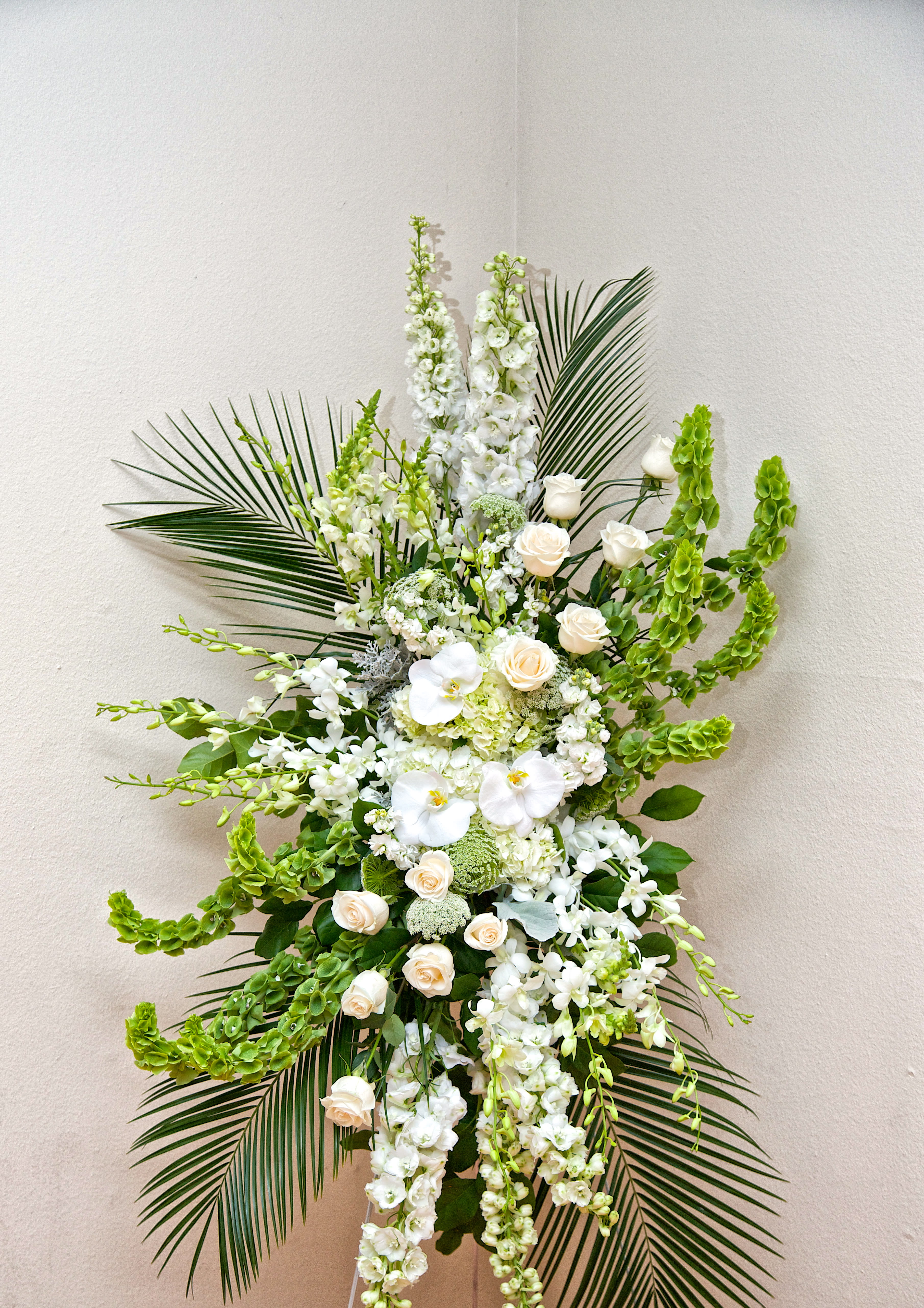 Pure Peace Standing Spray - Elegant and glorious, this classy white spray will express your sincere condolences. Orchids, roses, and statement greens are featured.