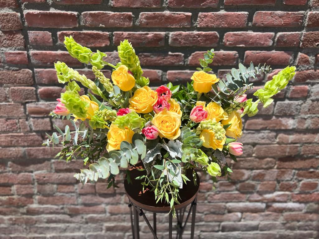 cheerful energy - composed of 12 yellow roses,10 pink tulips, bells of Ireland, tuberose and eucalyptus in a glass cylinder vase  