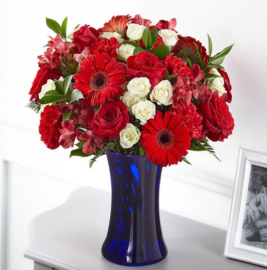 Hearts Embrace™ Bouquet Hearts Embrace™ Bouquet - The combination of red, white and blue pays patriotic tribute to the heroes in our lives who have passed. Our Hearts Embrace™ bouquet is designed with roses, gerbera daisies, alstroemeria and carnations in a bold blue vase to share a gesture of healing respect.