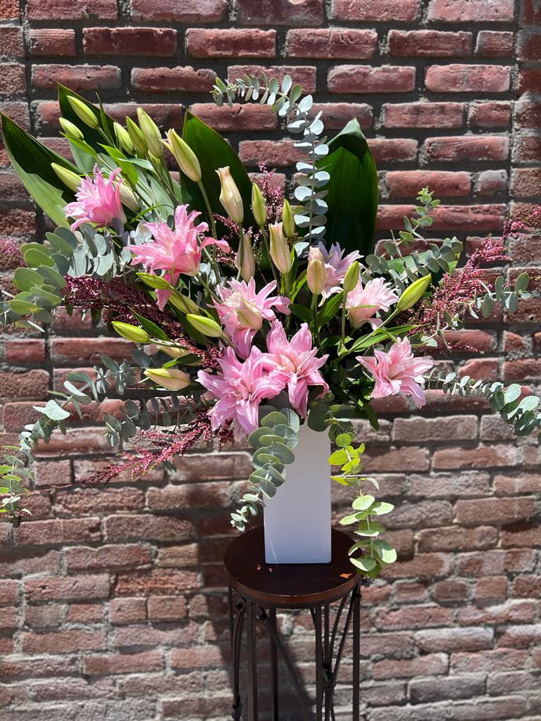 pink peace pink peace - composed of pink rose lillies or stargazer (as season allows) calcinia, ti leaf, baby blue eucalyptus and gunni all in a tall modern white ceramic vase.