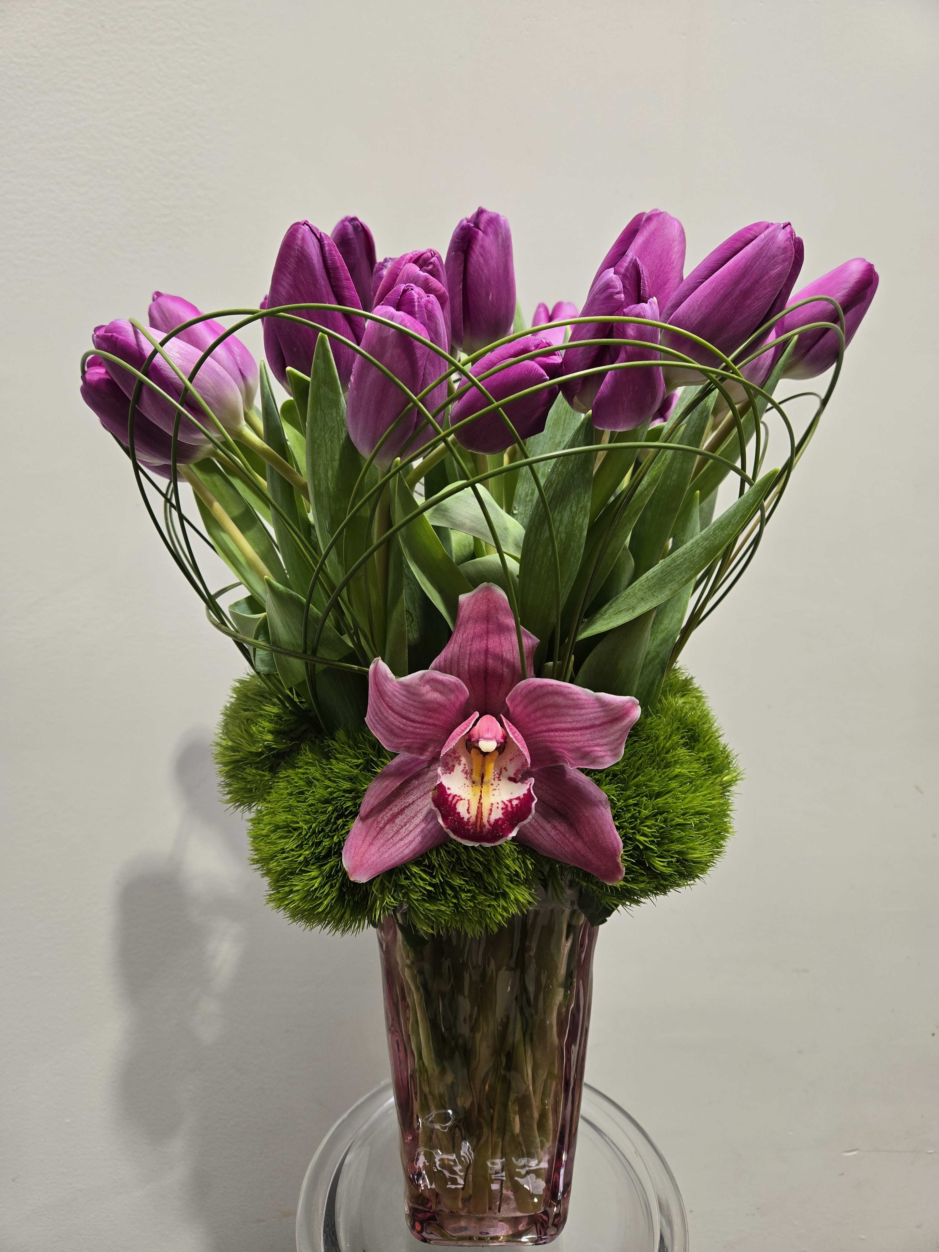 Lovely Purple Tulips - 30 purple tulips nicely displayed in a pink glass vase with grass loops and cymbidium orchid.