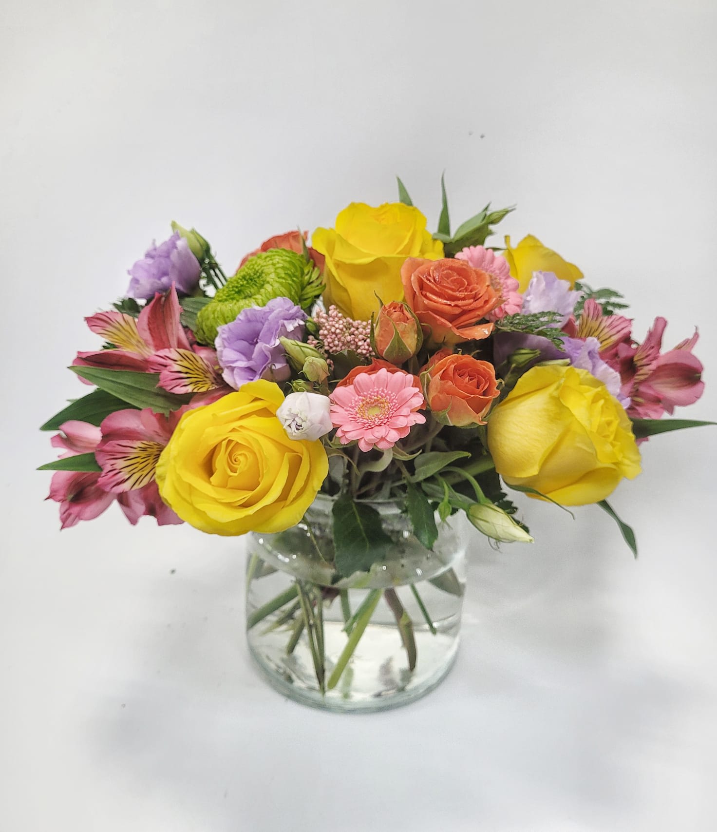 Suddenly Spring Suddenly Spring - Yellow roses mixed with assorted florals in orange, green and pink tones to brighten up any Mom’s day