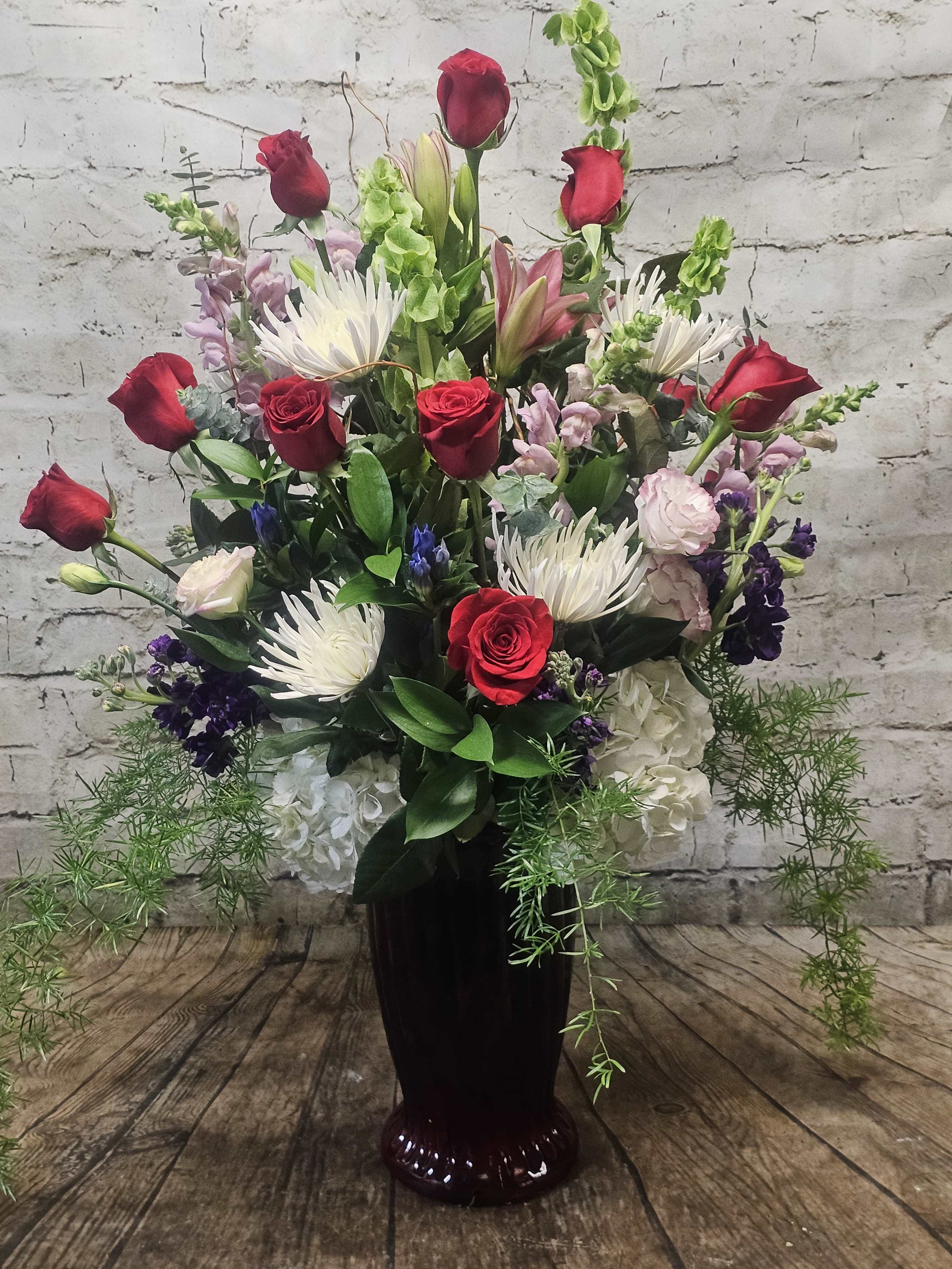 So In Love - A grand gesture. An oversized vase holds a dozen red roses plus hydrangea, snapdragons and more!