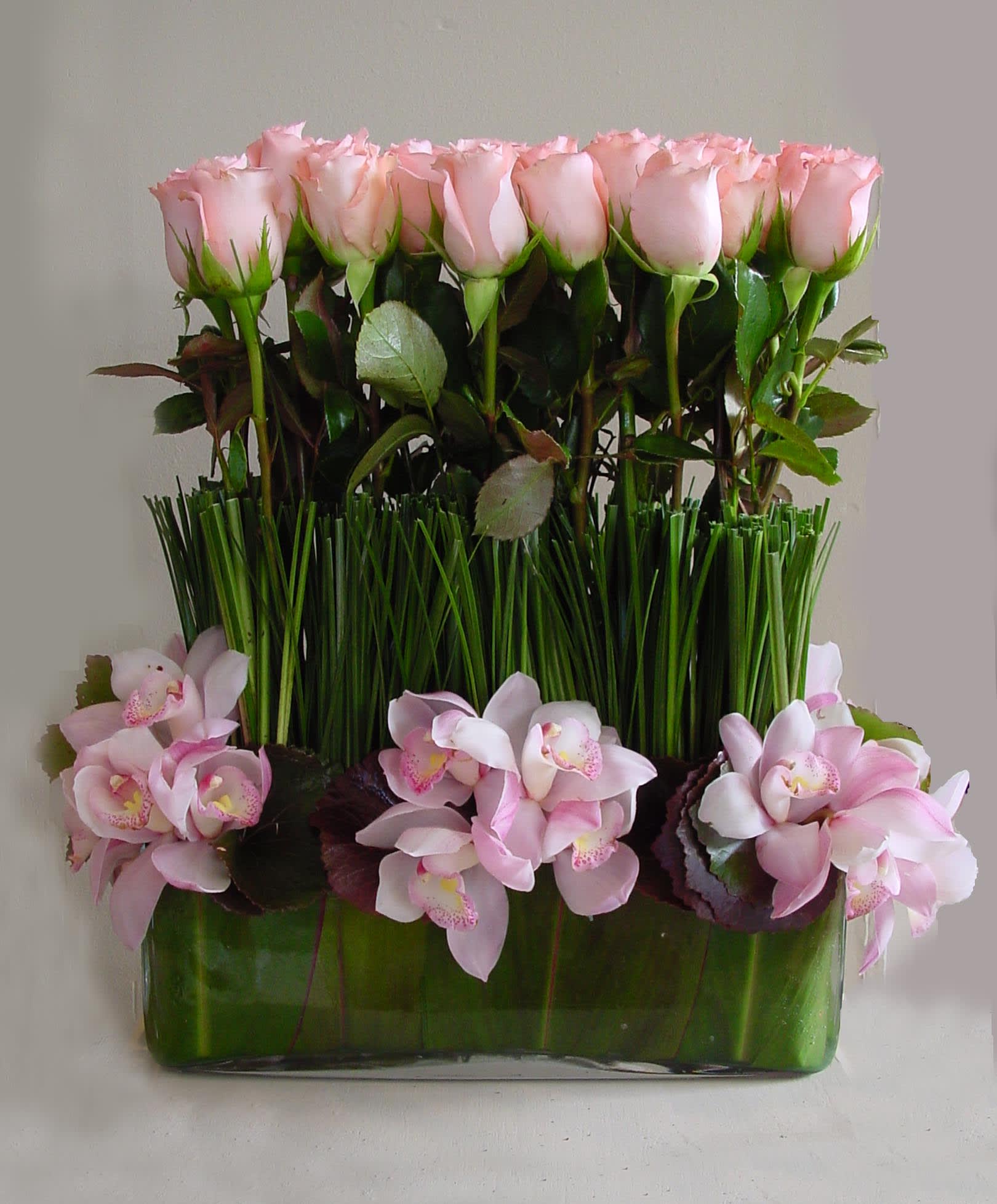 Sweet Touch - These stylish roses standing tall adorned with cymbidium orchids is a unique take on a simple rose arrangement. Let us know if you would prefer a different color, we'd be happy to change it up with a color other than pink that speaks to you.