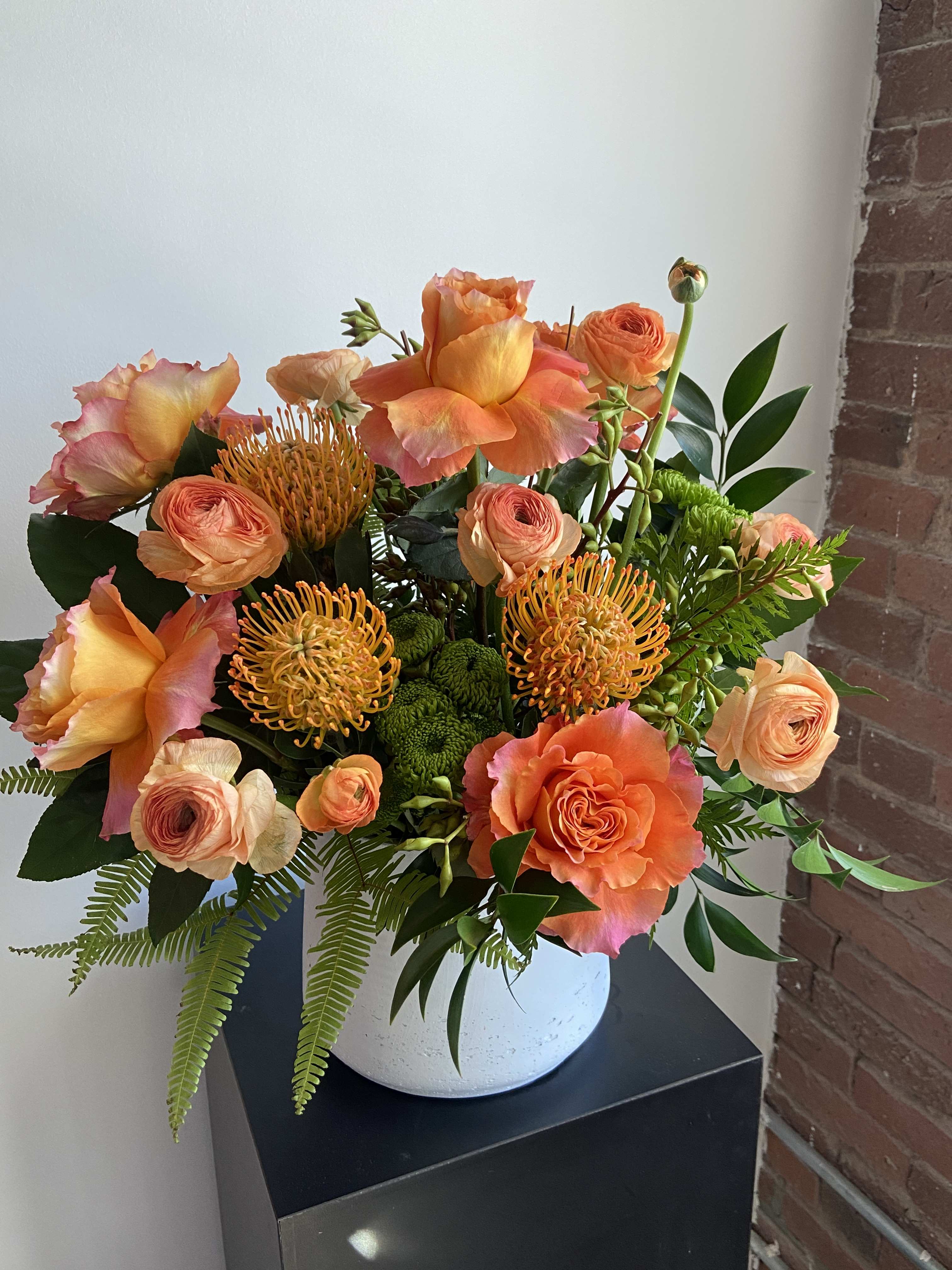 Orange Crush - This statement piece has the perfect dose of vitamin C! Bursting with orange free spirit roses, protea, ranunculus and ferns. It's a guaranteed crush!
