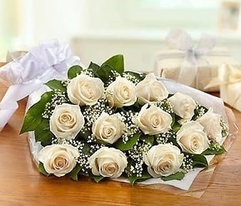 Dozen White Roses Hand-Tied Bouquet - A dozen white roses adorned with baby's breath and foliage wrapped in cellophane paper. 