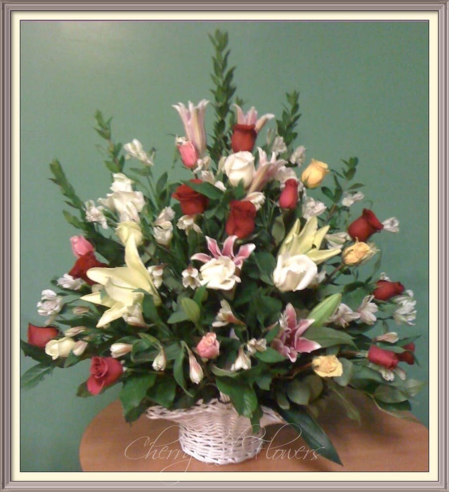 True Colors - This floral masterpiece features a fresh assortment of two dozen multi-color roses, stargazer lilies, and alstroemeria arranged in an elegant large white basket. 