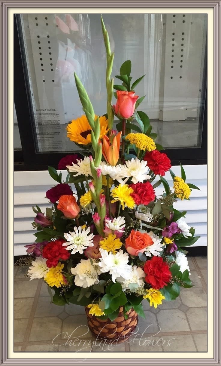 CF787 - Brighten a loved one's day with this colorful array of carnations, roses, lilies, gladiolus, alstroemerias, daisies, sunflowers, and foliage artfully arranged in an elegant woven basket. 