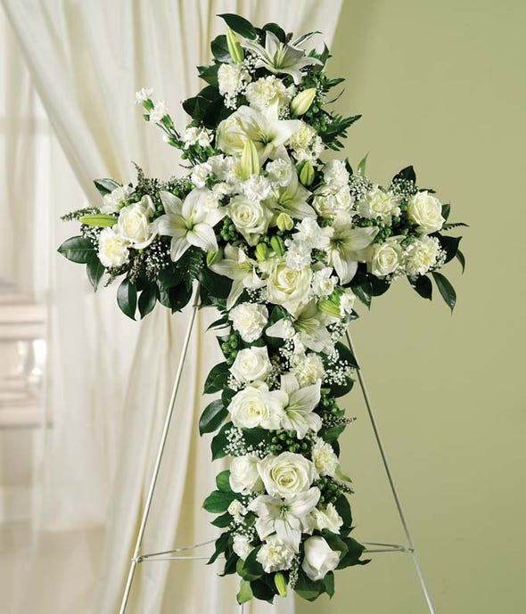 Honor Standing Cross (call for possible color changes and sizes) - Expertly designed, this cross shaped standing spray arrangement of white roses, lilies and carnations is a lovely way to honor a family member or friend. This arrangement is traditionally sent directly to the funeral home to be displayed on a stand sold as 18 inch 20 inch 22 inch 24 inch  at times up to 36 inch, Please call for sizes  Additional flowers can w be added to enhance the bouquet, We can also make the design on a smaller display  