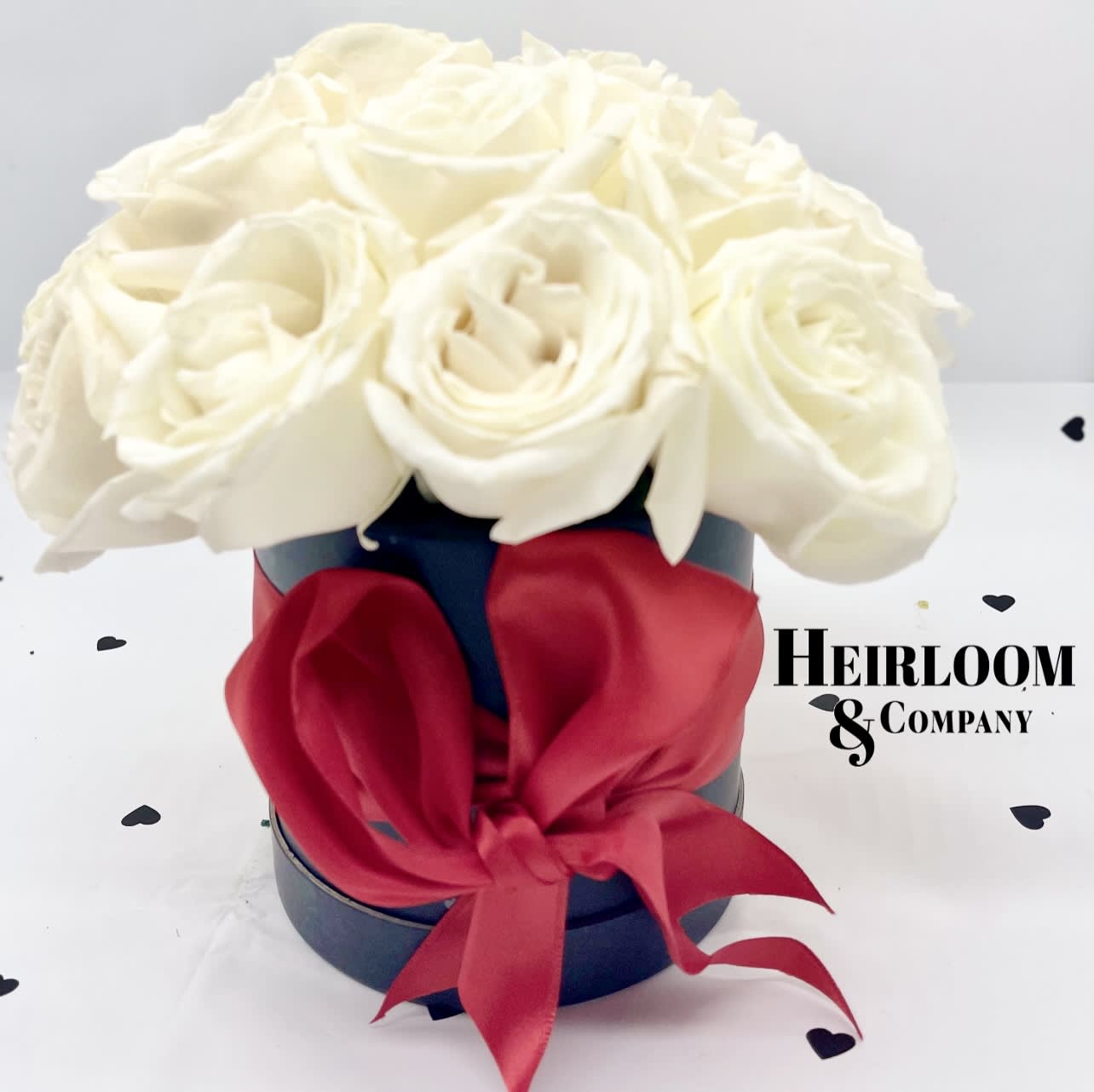 Queen of hearts Queen of hearts - Introducing 'The Queen of Hearts' Valentine’s Day arrangement, delicately crafted to captivate hearts. Nestled within a sleek matte black hat box, discover a stunning collection of premium white roses, reminiscent of a tranquil garden. Inspired by the regal allure of the Queen of Hearts from Alice in Wonderland, each bloom embodies elegance and grace. Complete with a tasteful oversized red satin bow.