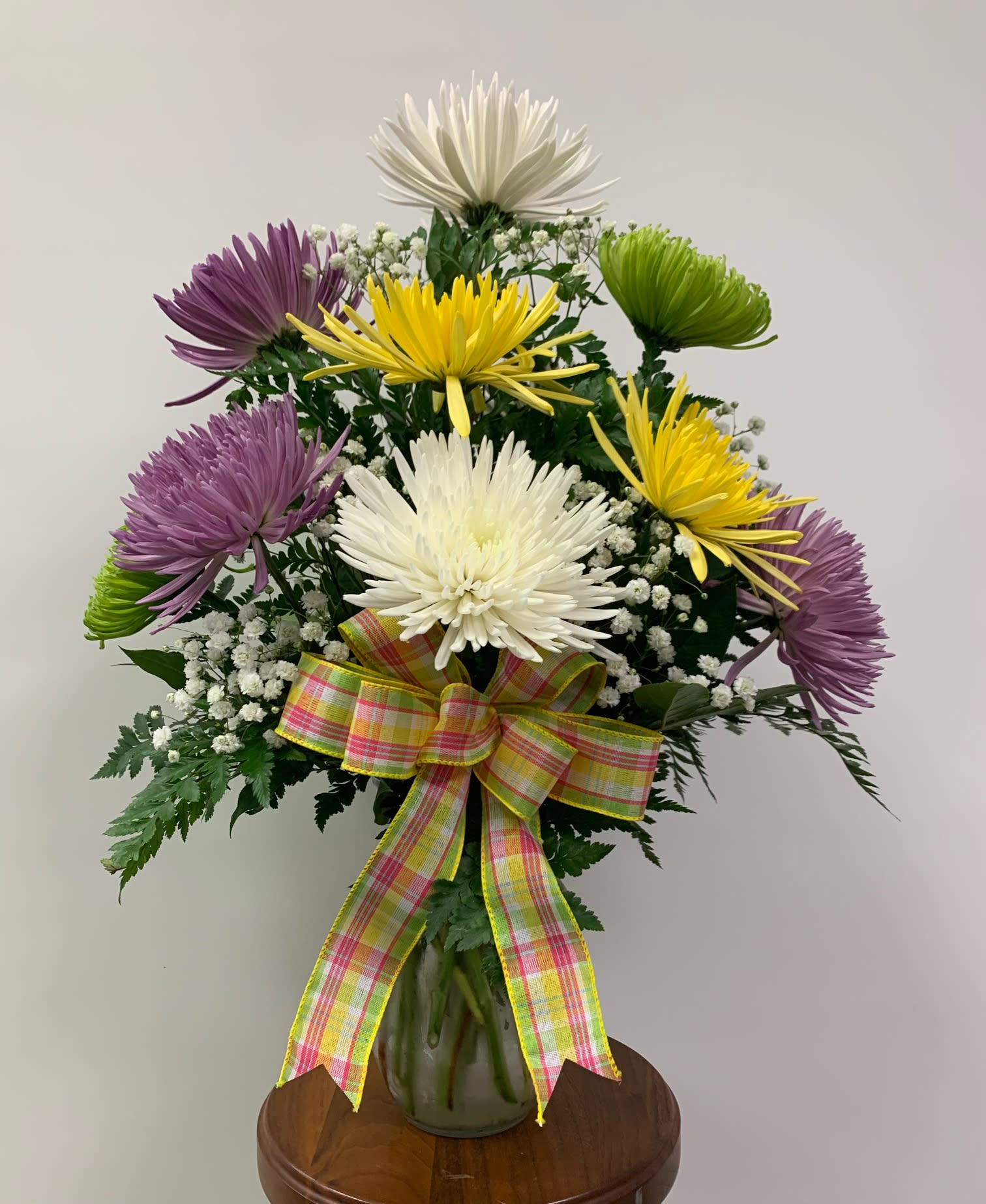 Mums The Word! - A lovely display of a dozen assorted fuji mums. Accented with baby's breath and a decorative bow.  Colors may vary due to availability. A perfect gift for Mom this Mother's Day! Orientation: All-around