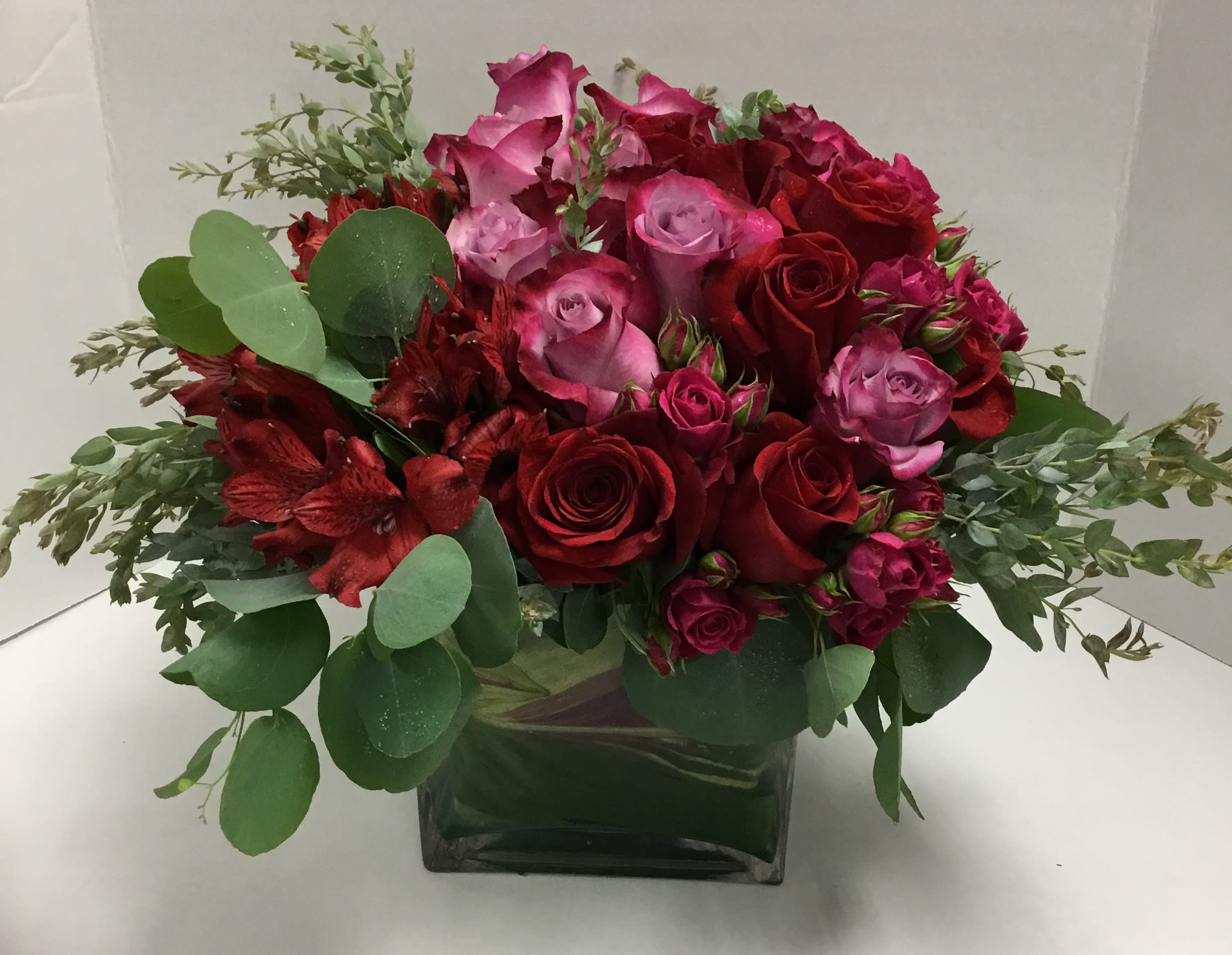 How Do I Love Thee - Lush arrangement of roses, alstromeria, spray roses and eucalyptus in a square glas leaf-lined vase