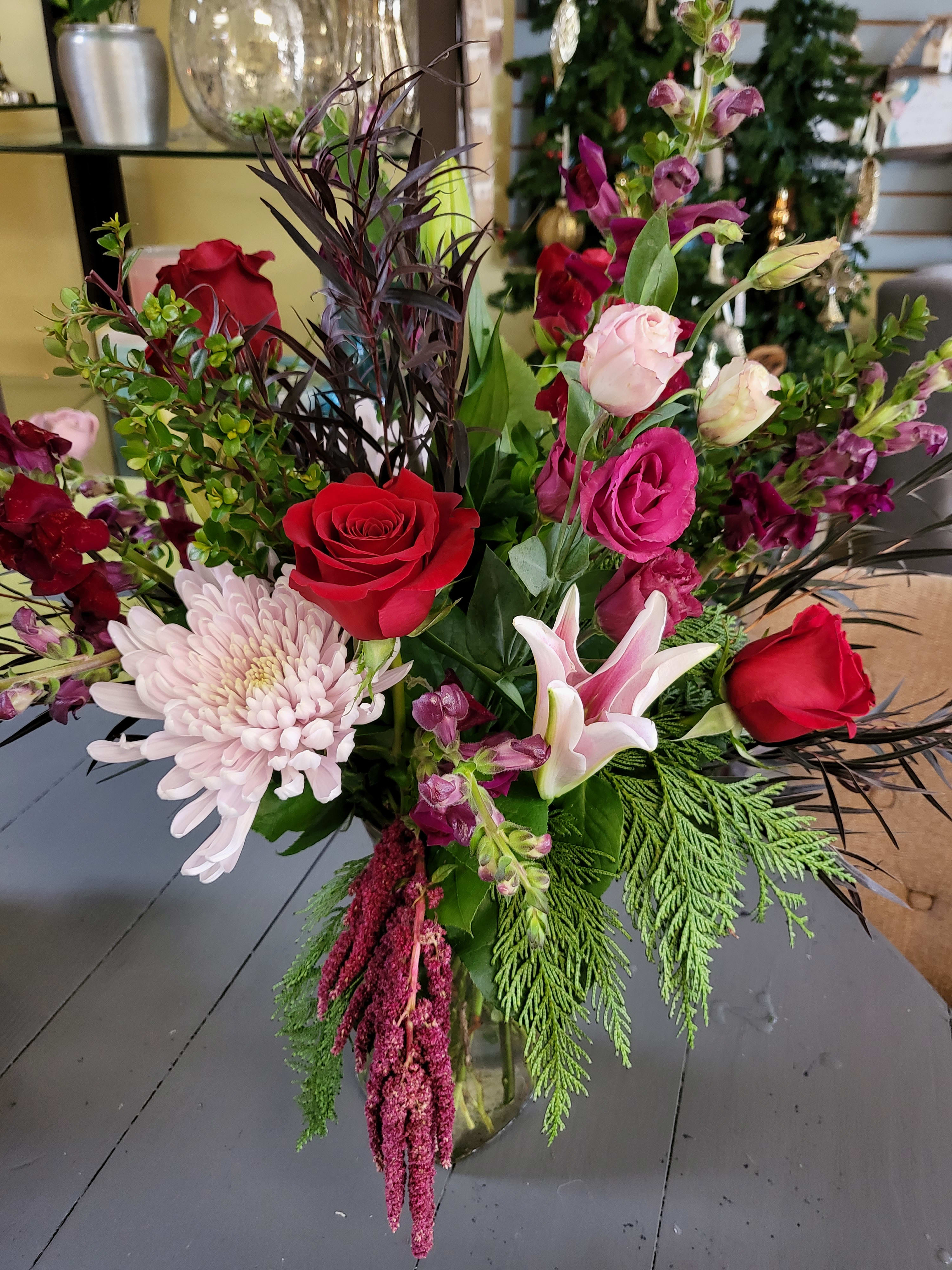 Blooming Red - Beautiful vased arrangement designed using roses, lilies, and beautiful mums. Perfect for that special someone.  Picture shown is premium version.