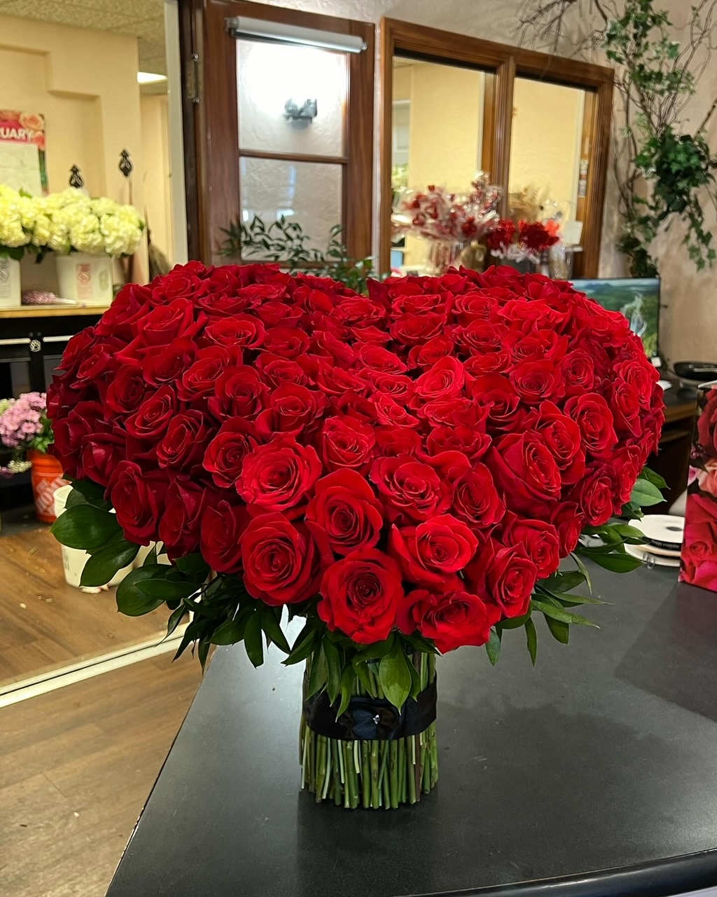 Love you so so much  -  A large heart covered in red roses.  The base is all rose stems, no vase needed.