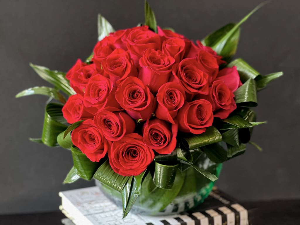 Modern design with 2 dozen red roses - Modern design with 2 dozen red roses in clear vase with greenery accent 