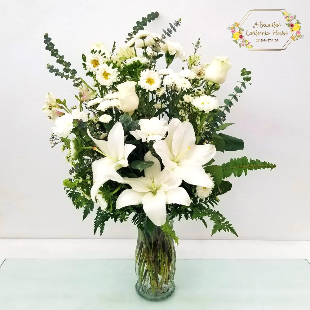 Amazing Grace - A beautiful arrangement of lilies, roses and other blooms in white and ivory tones. Accented by lush greens and arranged in a clear vase. Amazing Grace from A Beautiful California Florist, offering same day flower delivery service, Long Beach CA Approximate size: 20&quot; Tall x 18&quot; Width 