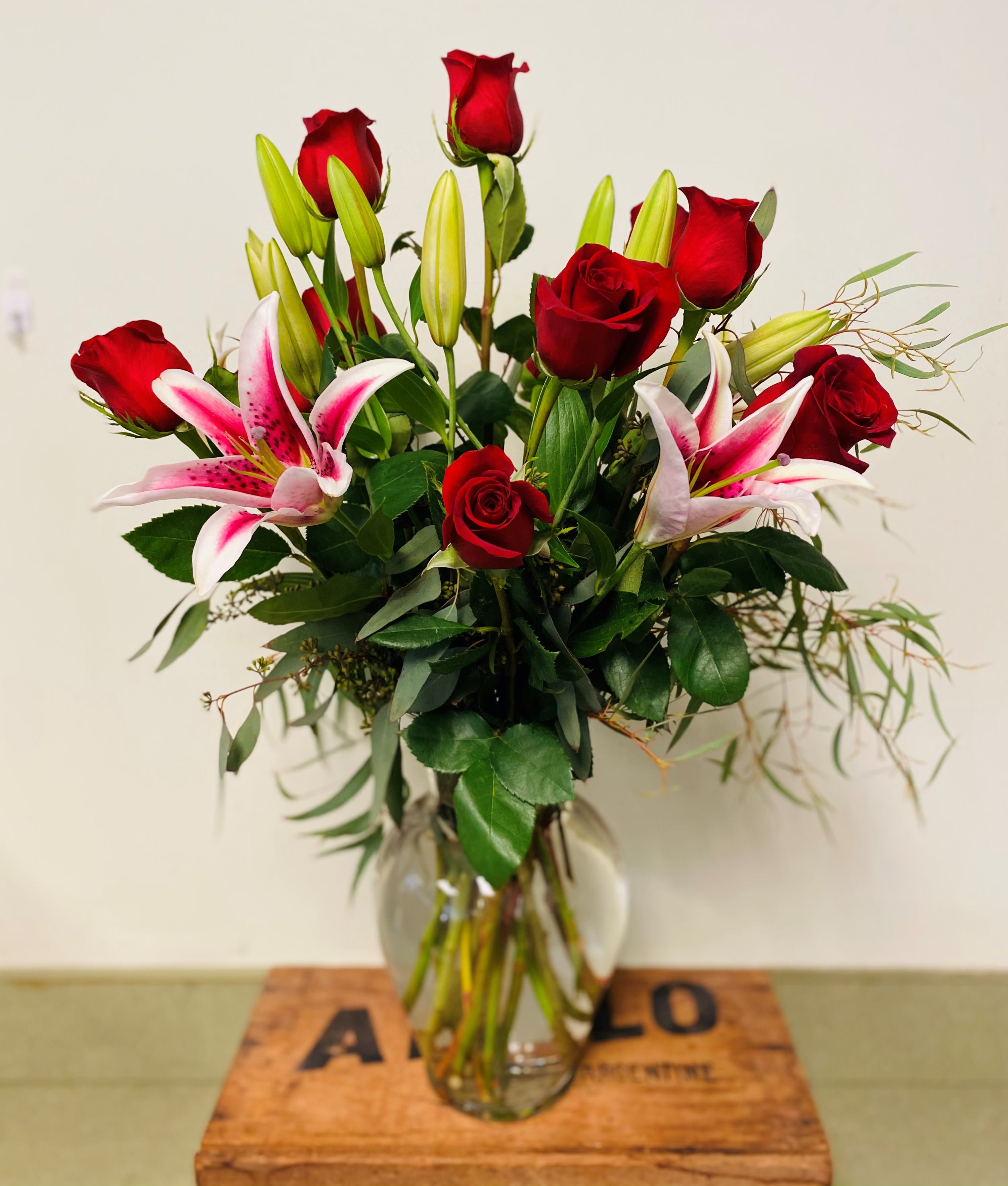 Dazzling Dozen  - One dozen long- stemmed Ecuadorian roses with Oriental lilies, expertly arranged in a tall clear glass vase with lush, tropical foliage. Pictured in red and pink; other colors are available 