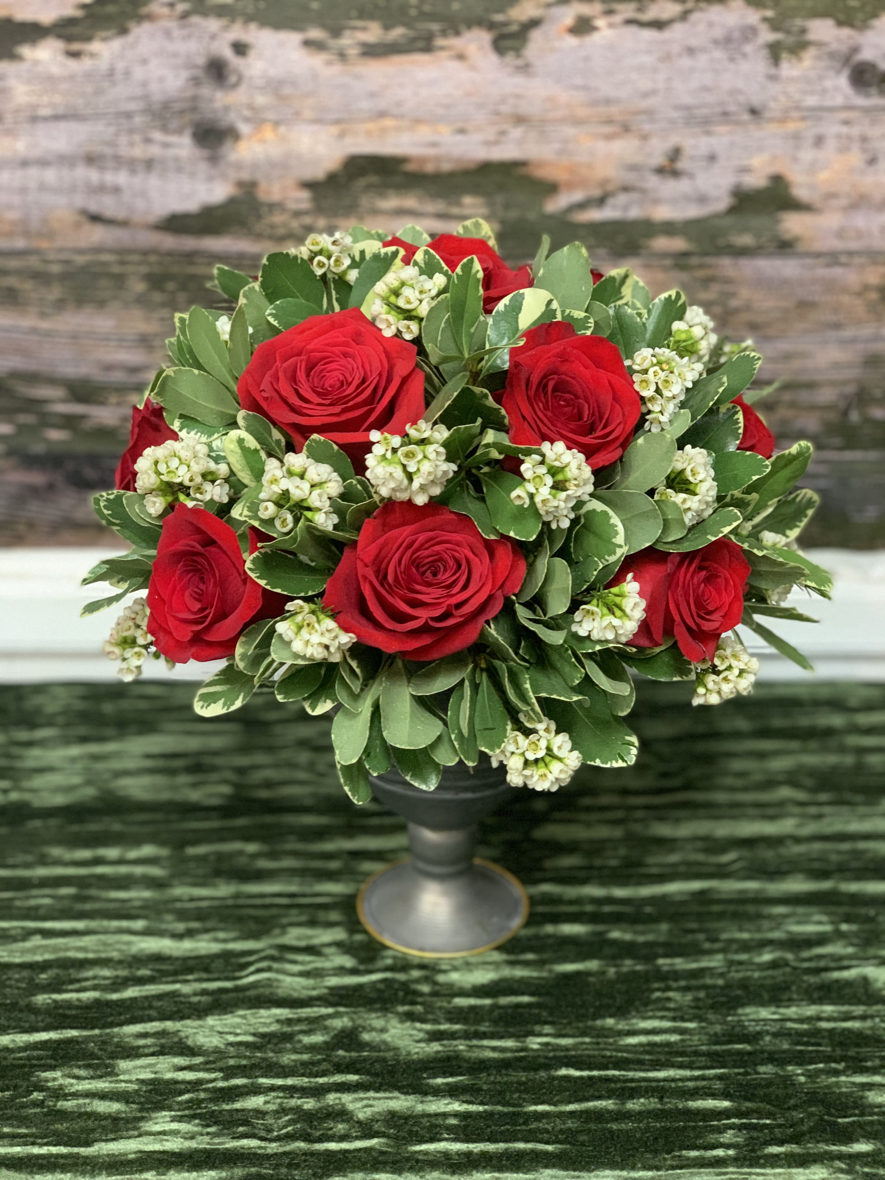 Rose Compote  - Red Roses, Waxflower, and Mixed Greenry Arrive in a Metal Compote. 