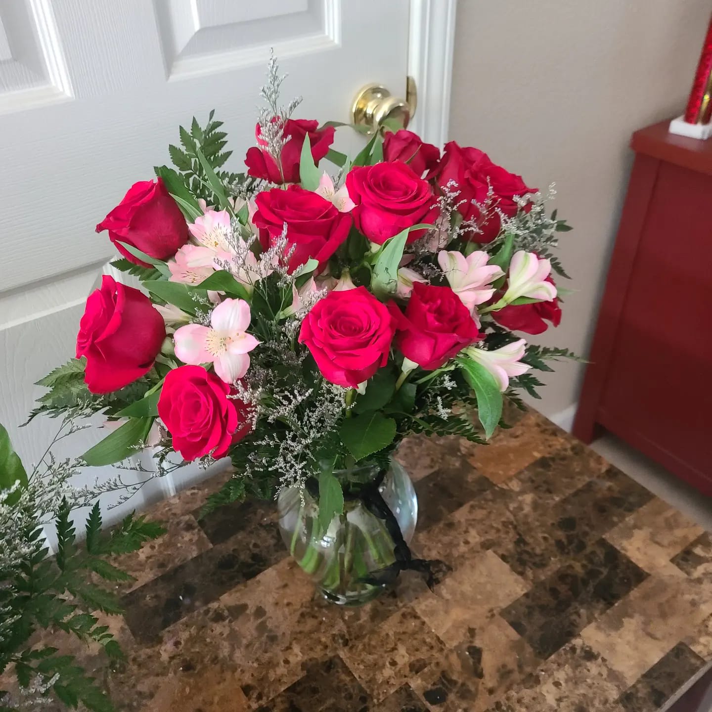 Katey's Dozen Roses - long-stem red roses in a vase mixed with filler flowers, filler, and greens.