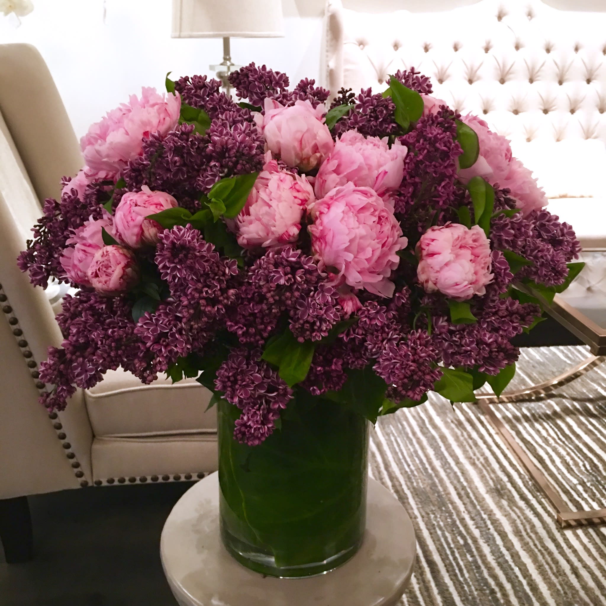 Mother's Love - As grand and sweet as a mother's love. This is an arrangement that will send a fragrant gesture that's sure to show just how big your love is. A large arrangement that stands in a large leaf-lined vase. and filled to the brim with aromatic lavender lilacs, and perfectly pink peonies. Send to yourself to enjoy (and smell!) or to someone you really want to show how much you appreciate them!  If you would like a scaled down version of this arrangement, no problem! Call us and let us know how we can customize this for you.