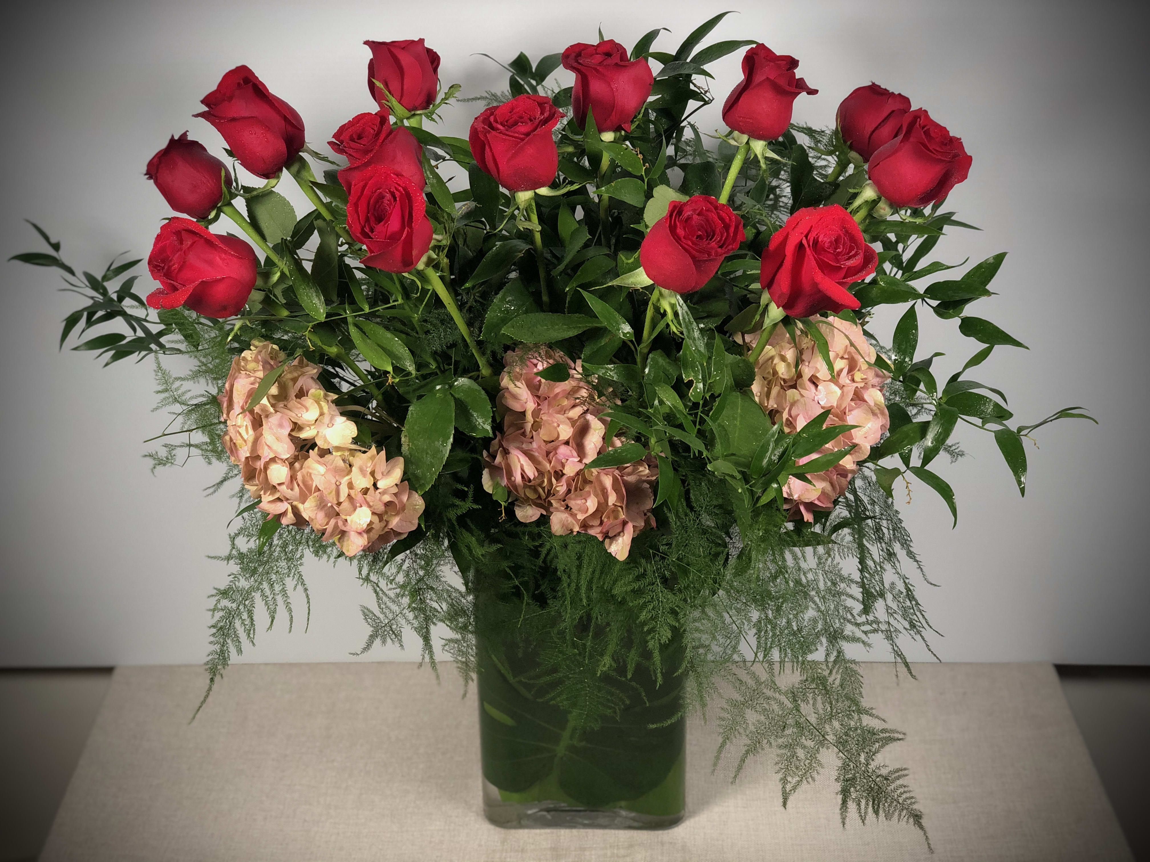 Sweet Valentines - Our luxurious version of the traditional dozen long-stem red roses... soft greens and fluffy hydrangeas add to vibrant red roses to take this Valentine's Day staple to a whole new level.