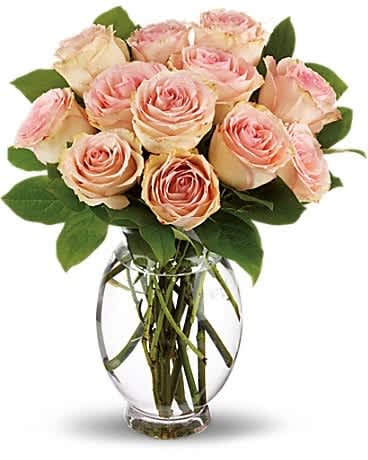 Delicate Dozen - As soft and delicate as the first blush of love, this rose bouquet carries a lot of romance. Gorgeous sweet pink roses arranged in a clear glass vase sends such a beautiful message of love, it just might leave you and your love blushing.