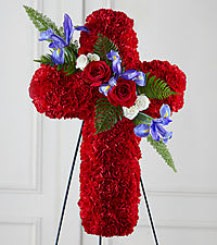 All red Carnation Cross - This thoughtful and meaningful tribute is a vibrant expression of faith. This graceful cross constructed with of bright red carnations, blue iris, roses and other complementary greenery makes a powerful statement that's sure to be remembered and appreciated at a wake, funeral or graveside burial service. It comes with a metal easel for a floor/ground-standing display. Measures approximately30&quot;H x 34&quot;W