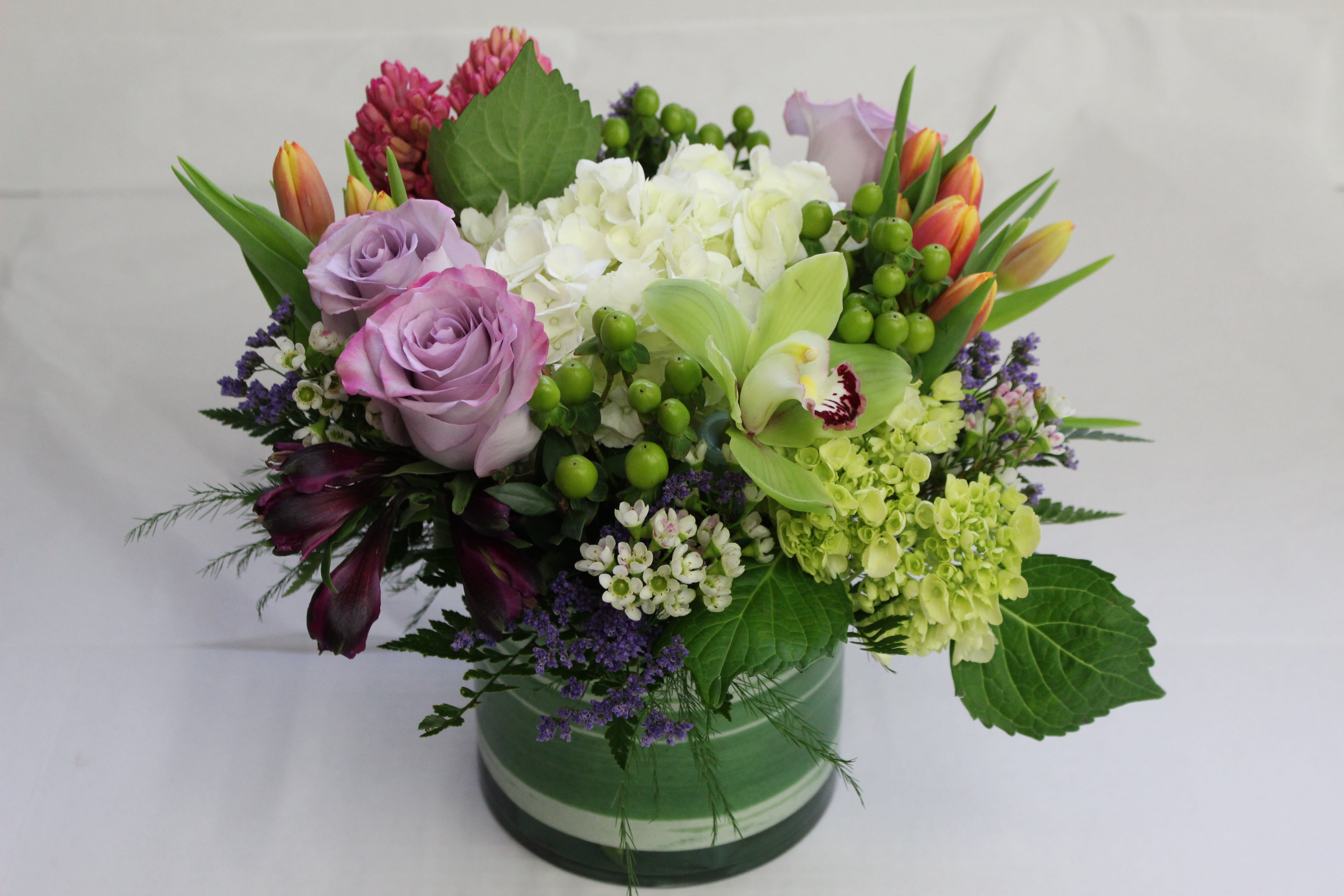 Hint of Lavender Hint of Lavender - This Lavender based arrangement is packed tightly in a leaf wrapped cylinder.