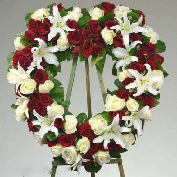 Heart of Peace - A beautiful red and white heart shaped wreath of premium roses and lilies, symbolizing love and warmth to show your sympathies for the beloved. *PICTURE SHOWN IS DELUXE  Standard: Approximately 20″ W x 21″ H Deluxe (As shown): Approximately 22″ W x 23″ H Premium: Approximately 24″ W x 25″ H
