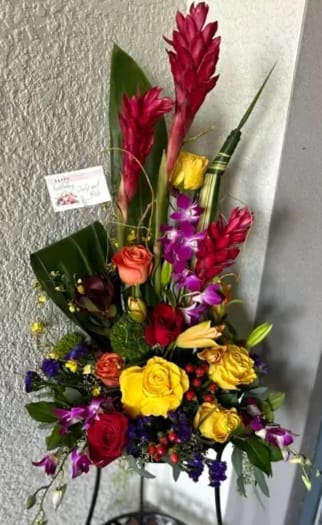 Tropical Majesty Tropical Majesty - Complementing the roses are pinkish-purple orchids that cascade gracefully, contributing to the arrangement's exotic feel.