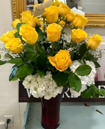 Sunshine Elegance Sunshine Elegance - Surrounding the roses are clusters of white hydrangeas, which provide a lush, soft contrast to the vivid yellows with their abundant, delicate petals.