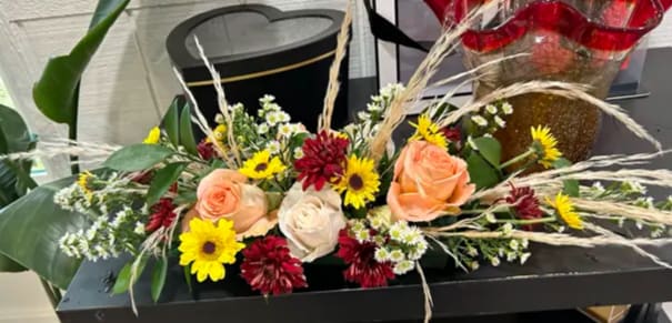 Autumn Whisper Autumn Whisper - The centerpiece is composed of soft peach and cream roses, symbols of appreciation and grace, alongside vibrant yellow daisies that bring a cheerful pop of color. Adding depth to the color palette are rich burgundy mums or dahlias, contributing a touch of autumnal warmth.