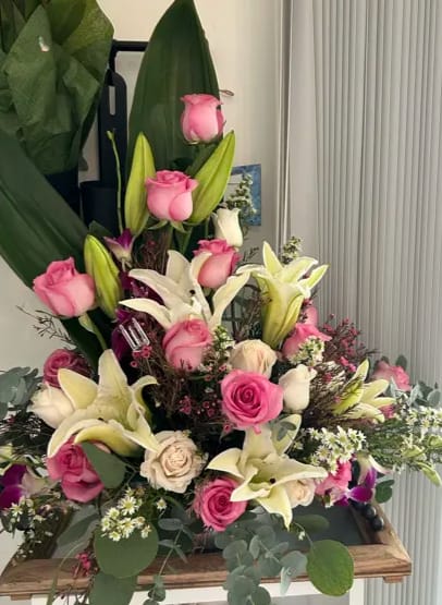 Blush of Dawn Blush of Dawn - Towering green leaves provide a dramatic backdrop to the bouquet, while elegant white lilies with their trumpet-shaped blossoms add a sense of sophistication and purity.