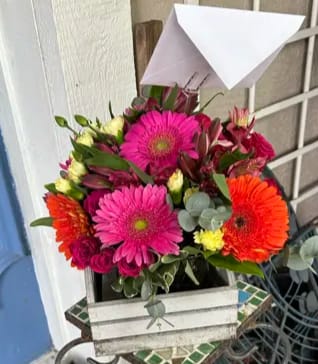 Vibrant Homestead Vibrant Homestead - The arrangement is a vibrant mix of flowers, including bold pink gerbera daisies and rich orange gerberas, which are the focal points with their large, striking blooms.