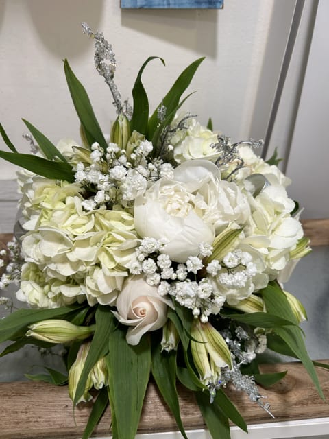 Winter's Grace Winter's Grace - The bouquet is accented with sprays of small white gypsophila, also known as baby's breath, lending a delicate, frothy texture. Interspersed throughout are slender leaves and green buds, which enhance the bouquet's natural and fresh look.