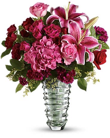 Swept Away Flower Arrangement Swept Away Flower Arrangement - A beautiful arrangement of pink Hydrangea, red Roses, pink Roses, red Spray Roses, hot pink Spray roses, pink Lilies and purple Carnations, in a clear glass vase with mixed greenery. **Vases will vary, we currently don't have this vase**