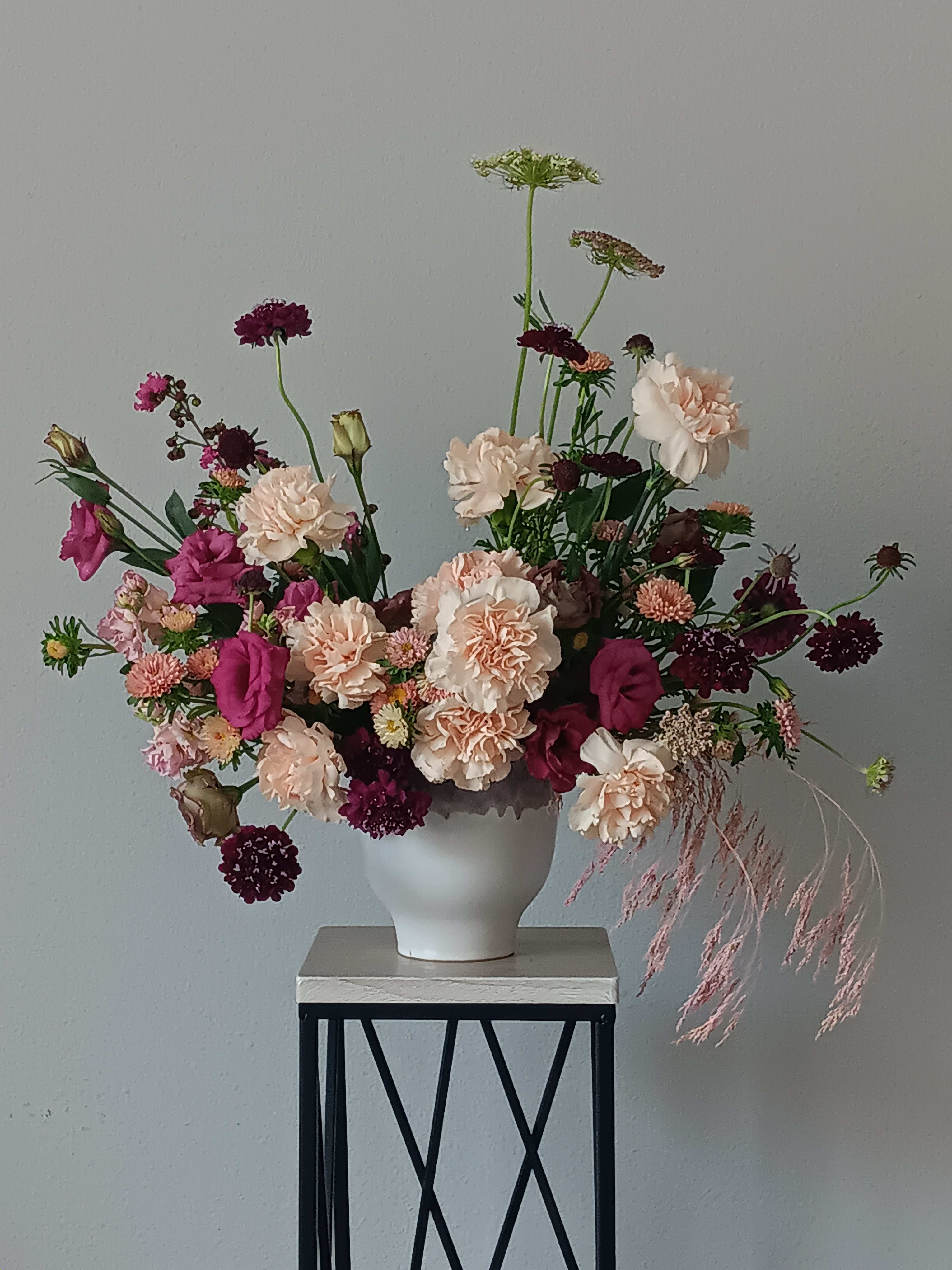 Hold Me Close Bouquet - Make it a special day! This passionate bouquet of lovely blush carnations, burgundy scabiosa, purple lisianthus, peach stock, artfully arranged in our pretty ceramic vase, is one she'll hold close to her heart forever.  Orientation: All-Around  SUBSTITUTION POLICY – Always deliver the freshest flowers! Please note the bouquet pictured reflects our original design.  If the exact flowers or container in this arrangement are not available, our local florists will create a beautiful bouquet with the freshest available flowers.