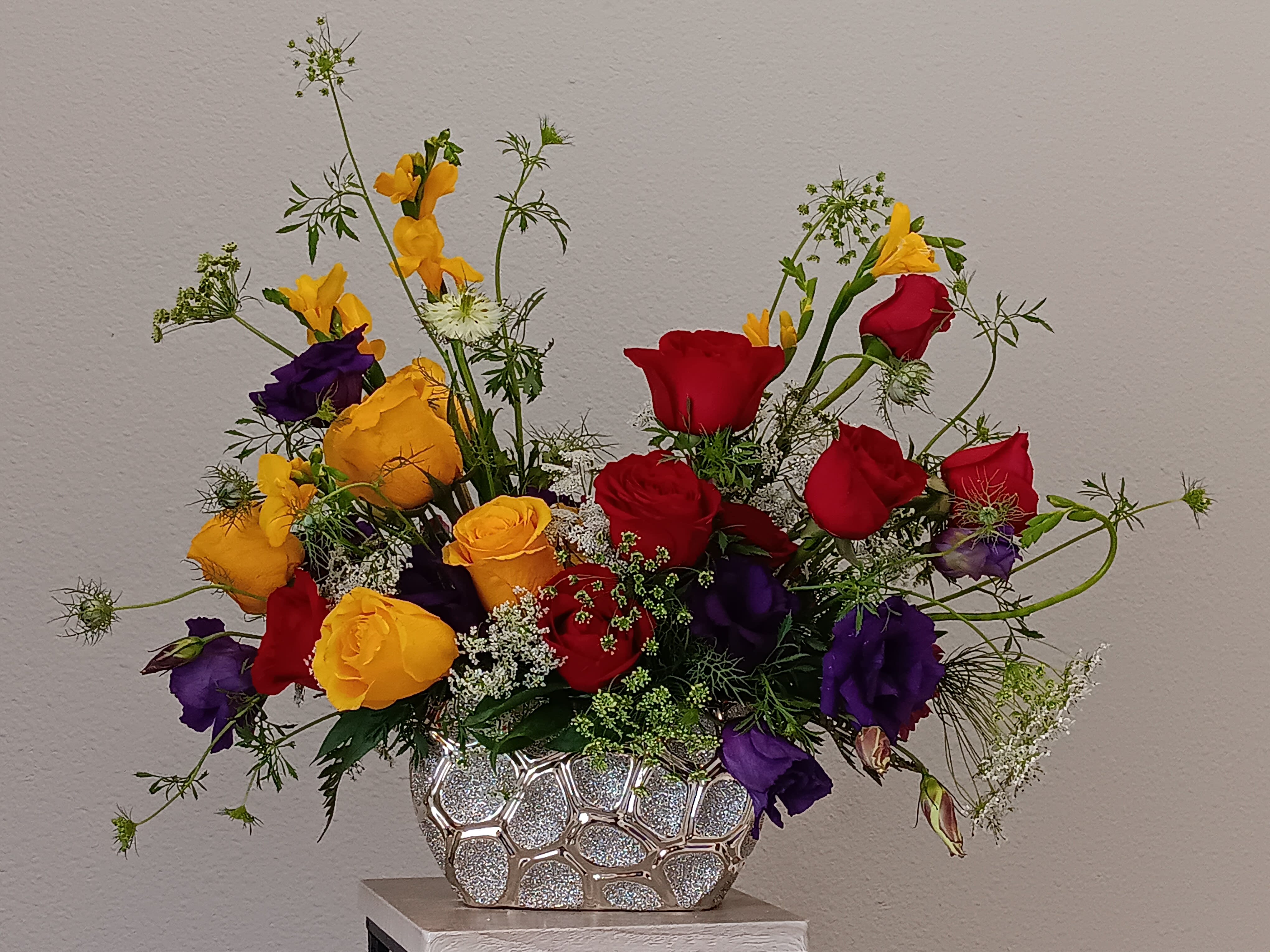 Pure Happiness - A sunny yellow freesia and yellow roses bouquet gets an autumnal spin with the addition of pretty purple lisianthus and rich red roses . The cheerful autumn floral arrangement is rich with color, making it a stylish, energizing pick for any occasion.  Presented in a lovely gold ceramic vase Orientation: All-Around  SUBSTITUTION POLICY – Always deliver the freshest flowers! Please note the bouquet pictured reflects our original design.  If the exact flowers or container in this arrangement are not available, our local florists will create a beautiful bouquet with the freshest available flowers.