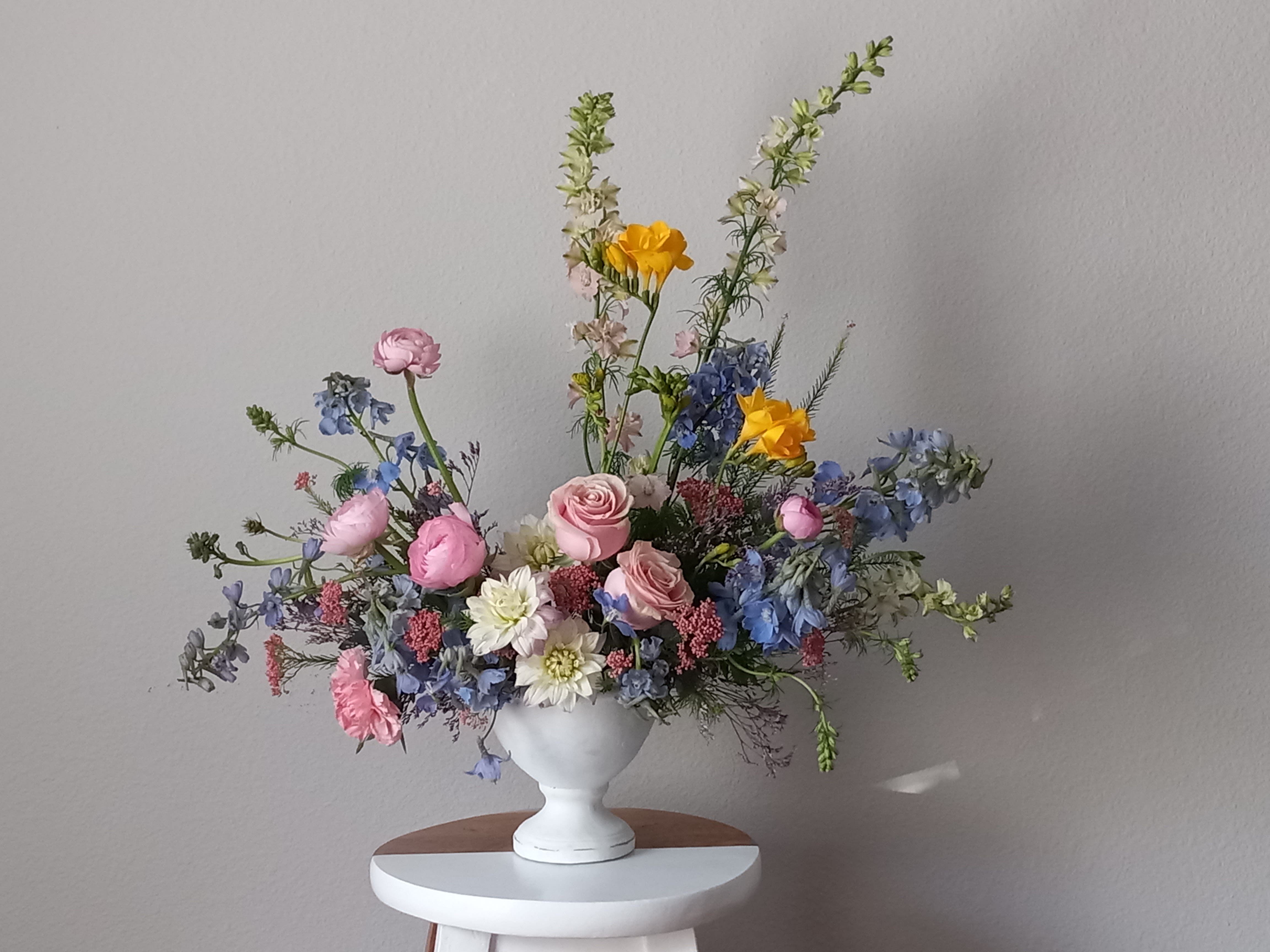 Dreaming of Blue - Like wispy clouds in a bright blue sky, this beautiful bouquet of pink and blue flowers in a stained ceramic vase a refreshing gift for any occasion. This breathtaking bouquet includes blue delphinium, yellow freesia, light pink ranunculus, light pink dahlia,  pink roses, pink carnations, pink larkspur, light blue delphinium, pink waxflower, seeded eucalyptus, and leatherleaf fern.   Orientation: All-Around  SUBSTITUTION POLICY – Always deliver the freshest flowers! Please note the bouquet pictured reflects our original design.  If the exact flowers or container in this arrangement are not available, our local florists will create a beautiful bouquet with the freshest available flowers.