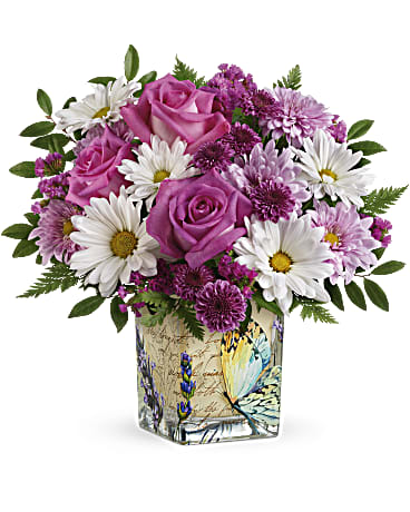 Vintage Butterfly Bouquet - Make Mom's spirit soar with this vintage-inspired Mother's Day vase, adorned with whimsical butterflies and bursting with the prettiest pink roses and daisies! Hot pink roses, purple button spray chrysanthemums, lavender cushion spray chrysanthemums, white daisy spray chrysanthemums and raspberry sinuata statice are arranged with leatherleaf fern and huckleberry. Delivered in a Vintage Butterfly Cube. Orientation: All-Around