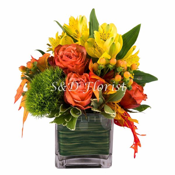 Yellow Daze - In a 4&quot; square glass vase lined with ti leaf containing yellow alstroemerias, orange roses, orange gerbera daisies, green dianthus and peach hypericum accentuated with oak leafs.  Dimensions: 6&quot;T x 5&quot;W