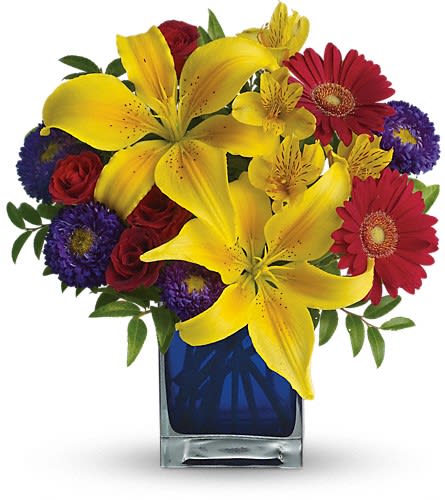 Teleflora's Blue Caribbean - Martinique St. Maarten any tropical paradise is the perfect setting for this explosively colorful bouquet in a chic blue contemporary cube vase. Can't go just now? Bring the island home. The exciting bouquet includes yellow Asiatic lilies red miniature gerberas purple Matsumoto asters red spray roses and yellow alstroemeria accented with fresh greenery. Delivered in a blue contemporary glass cube vase.Approximately 12&quot; W x 13&quot; H Orientation: All-Around As Shown : T05N440ADeluxe : T05N440BPremium : T05N440C