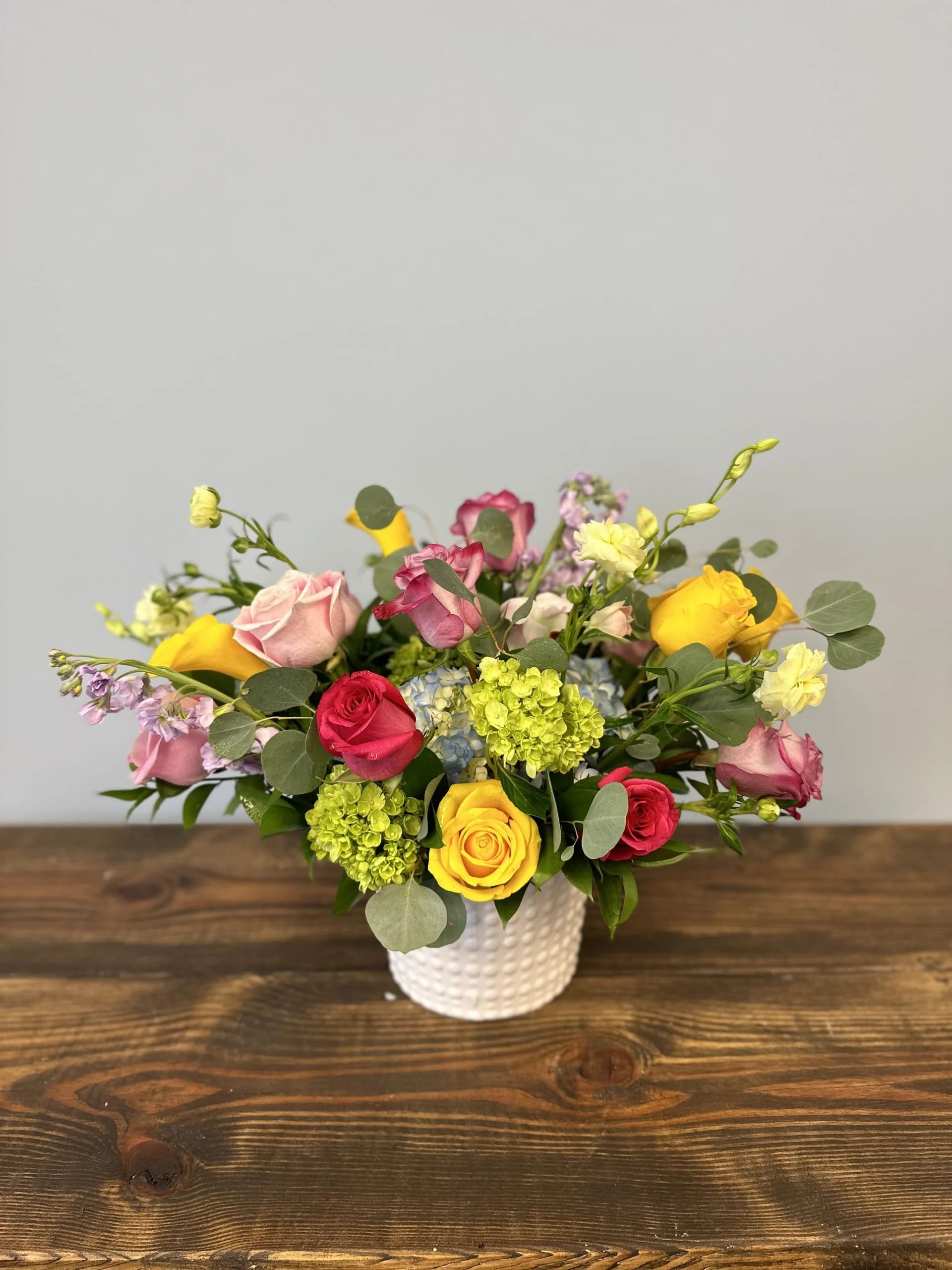 Ellie - Beautiful spring mix full of all the colors: pink yellow, blue, green, purple, etc.  Includes roses, hydrangea, and so much more. A spring mix anyone would love!