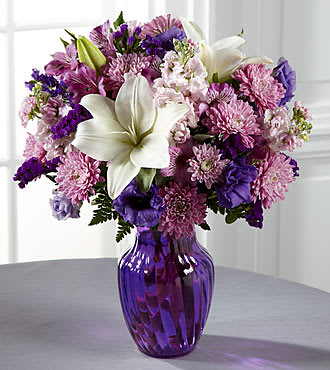 Shades of Purple Shades of Purple - A vibrant purple arrangement of lavender Stock, purple Lisianthus, lavender Cushion mums, purple Alstroemeria, purple Statice, and white lilies with greens in a purple vase. **** We currently don't have this vase but we will substitute one as similar as possible and if we don't have a purple vase we will use a clear and add a few additional flowers***