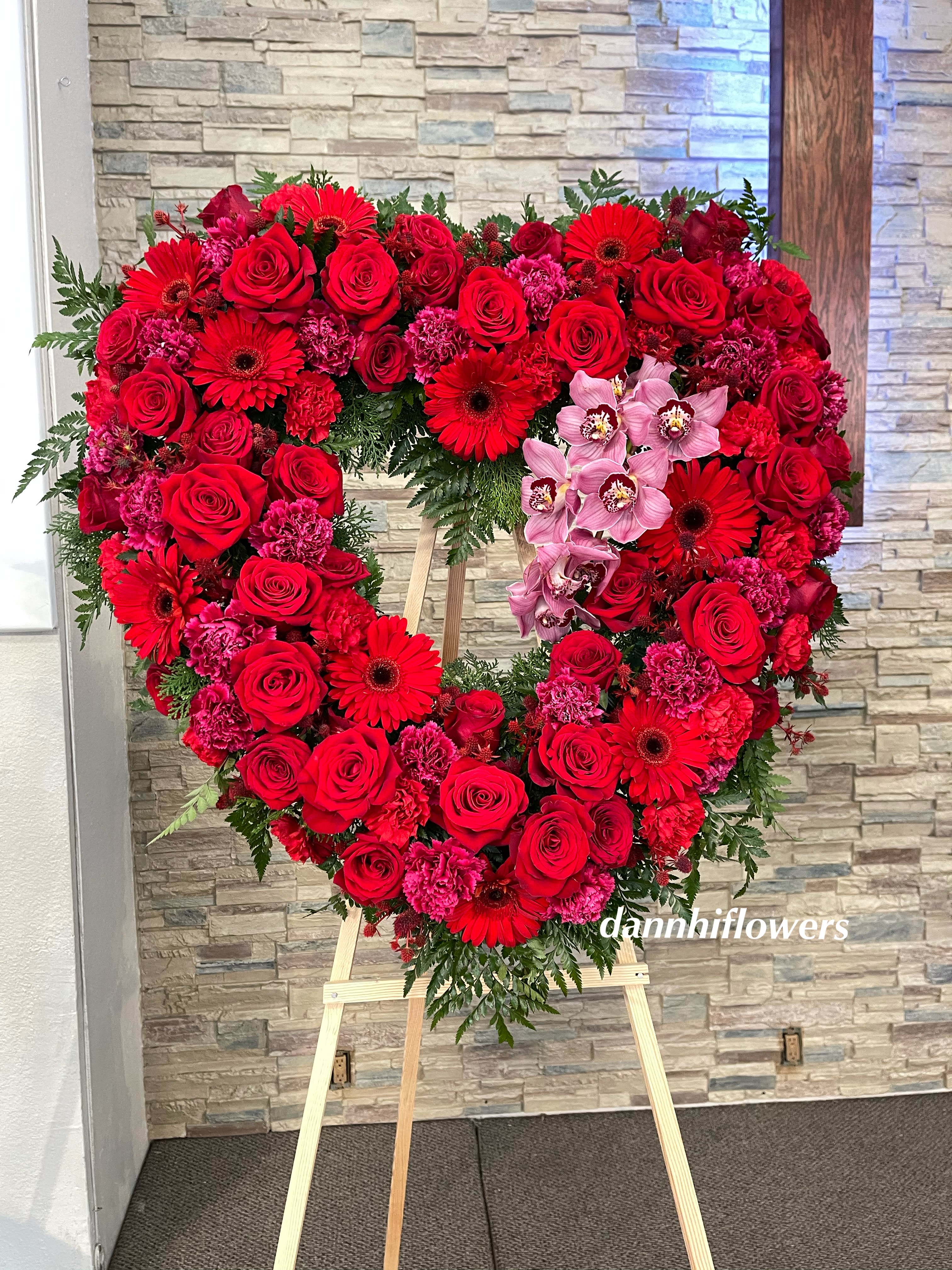 Sympathy open heart all red - A red open heart standing arrangement with seasonal red flowers and orchids