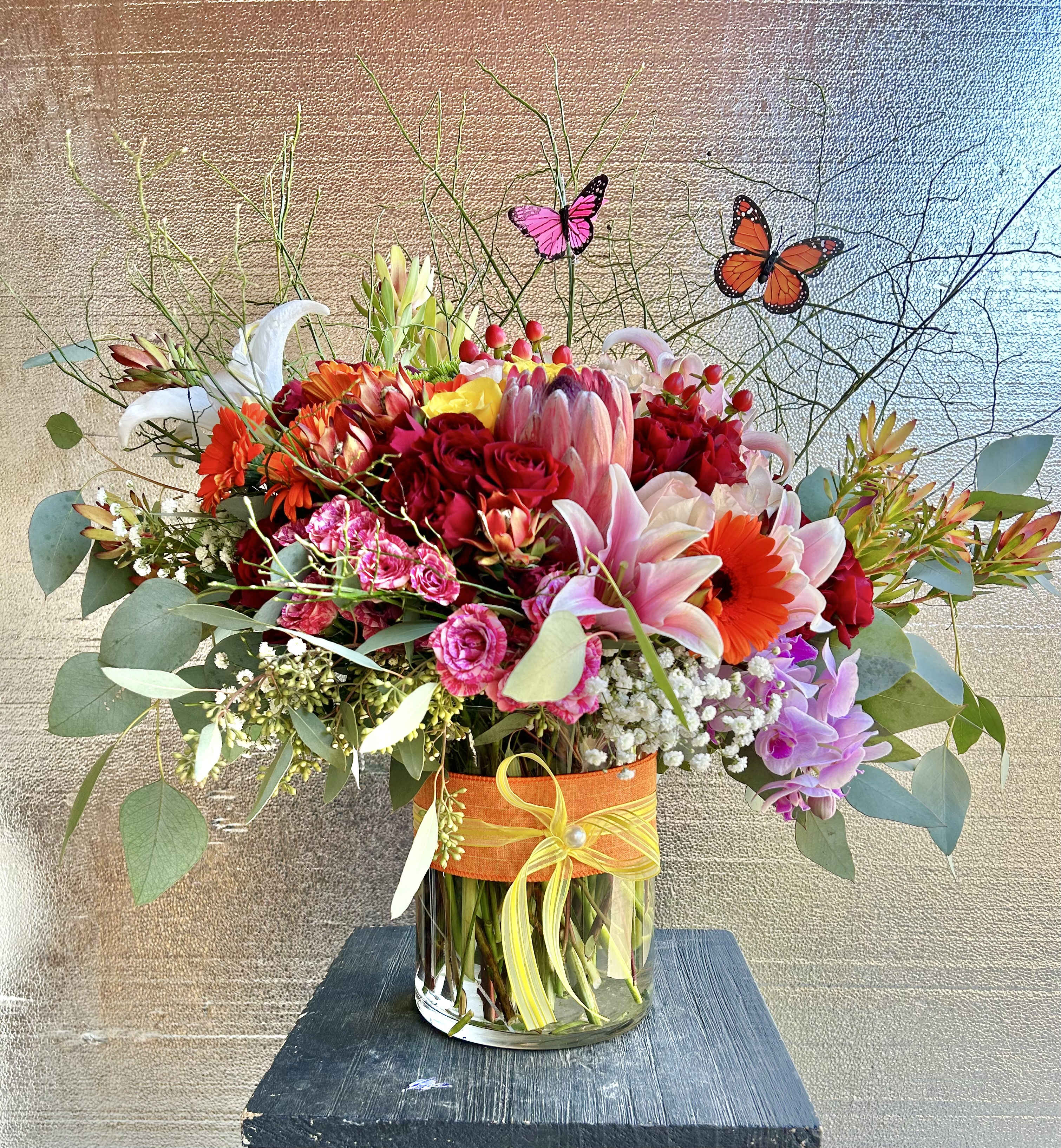 Blossoms of Love - Beautiful springtime arrangment of orchids, lilies, roses, tropical, red berry, and green accents in a vase. 