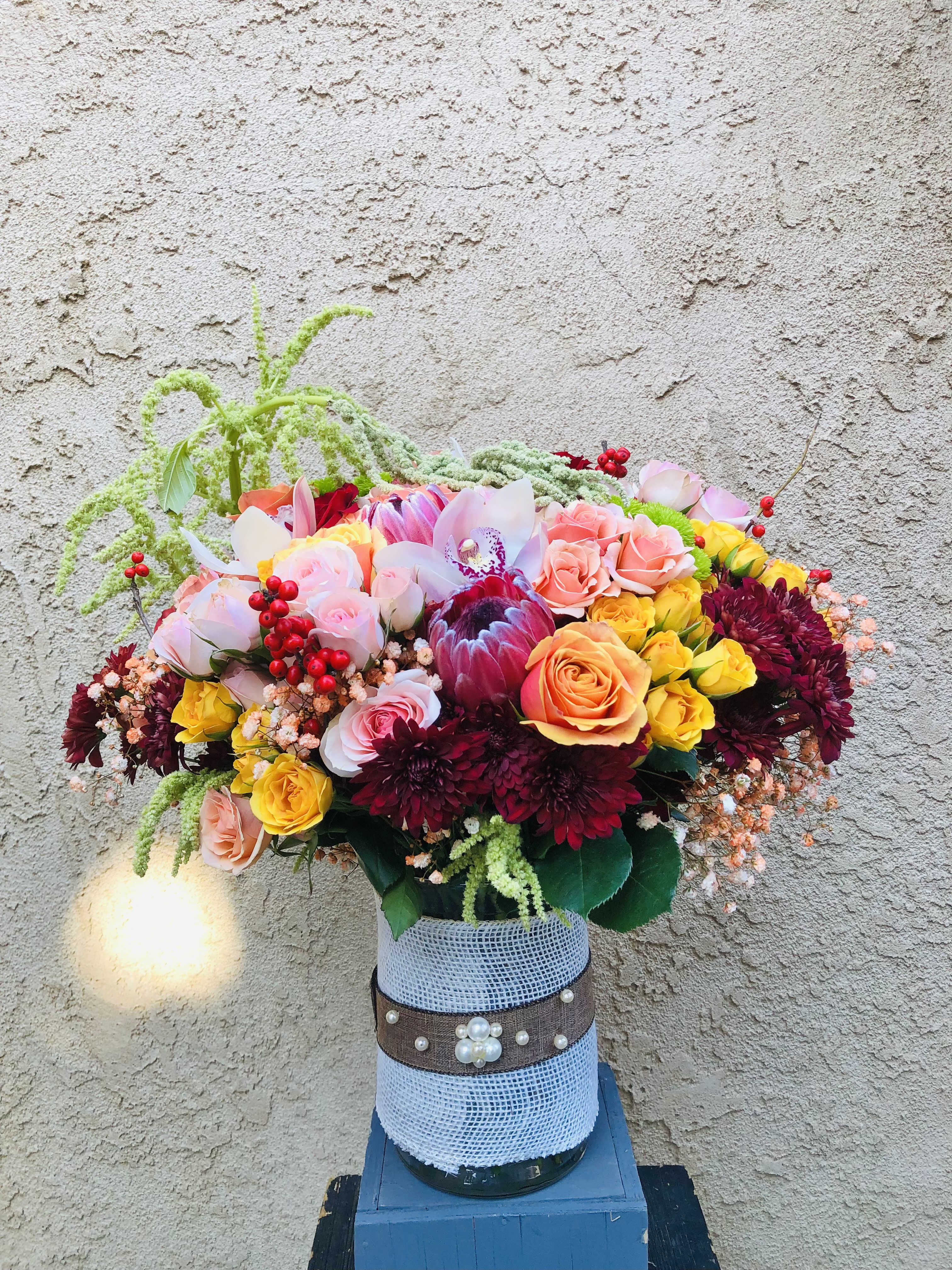 Radiance Blooms - Beautiful pink, maroon, yellow arrangment with roses, orchids, tropical, berries, and green accents. 