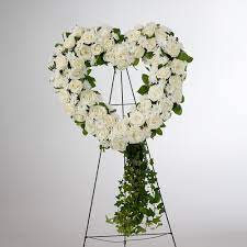 Love in our Hearts by BloomNation™ Love in our Hearts by BloomNation™ - An all white tribute, this heart shaped easel shows your everlasting love. Featuring a variety of white flowers and greenery, this heart with a trail of ivy compliments the beauty of life.