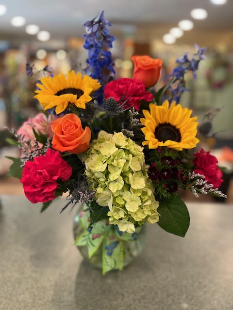 Summer Garden (SG) - The bright colors of Summer! Flowers such as Green Hydrangea, Orange Roses, Dark Blue Delphinium, Sunflowers and more. Sure will brighten their day. 