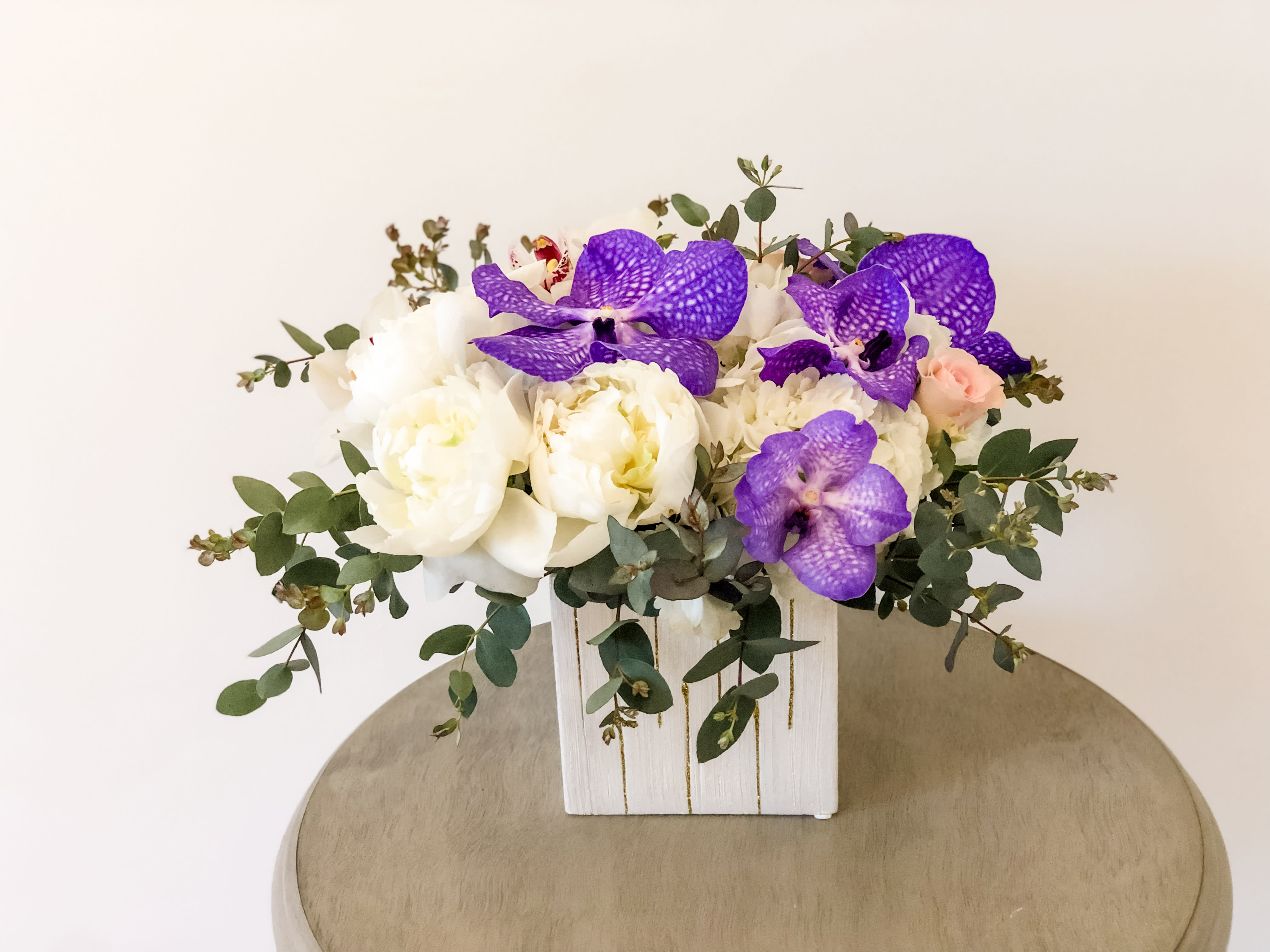 Peonies bloom - A pleasing combination of white orchids, white peonies, panda purple orchids  and purple vanda orchid fresh premium flowers mixed in an impressive and balanced design. Measures 10H x 10D. P.S Please note, we cannot guarantee specific flowers or colors. We will maintain the style and palette of each arrangement and guarantee it is designed with fresh seasonal bloom sand foliage. Please add to notes any specific requests. Dear customers In Some reason peonies out of season the florist will be replaced to garden roses .     